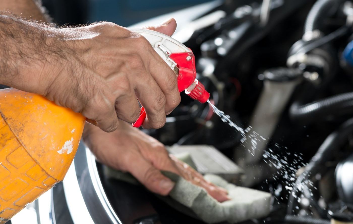 man spraying degreaser to prep an engine for a detail