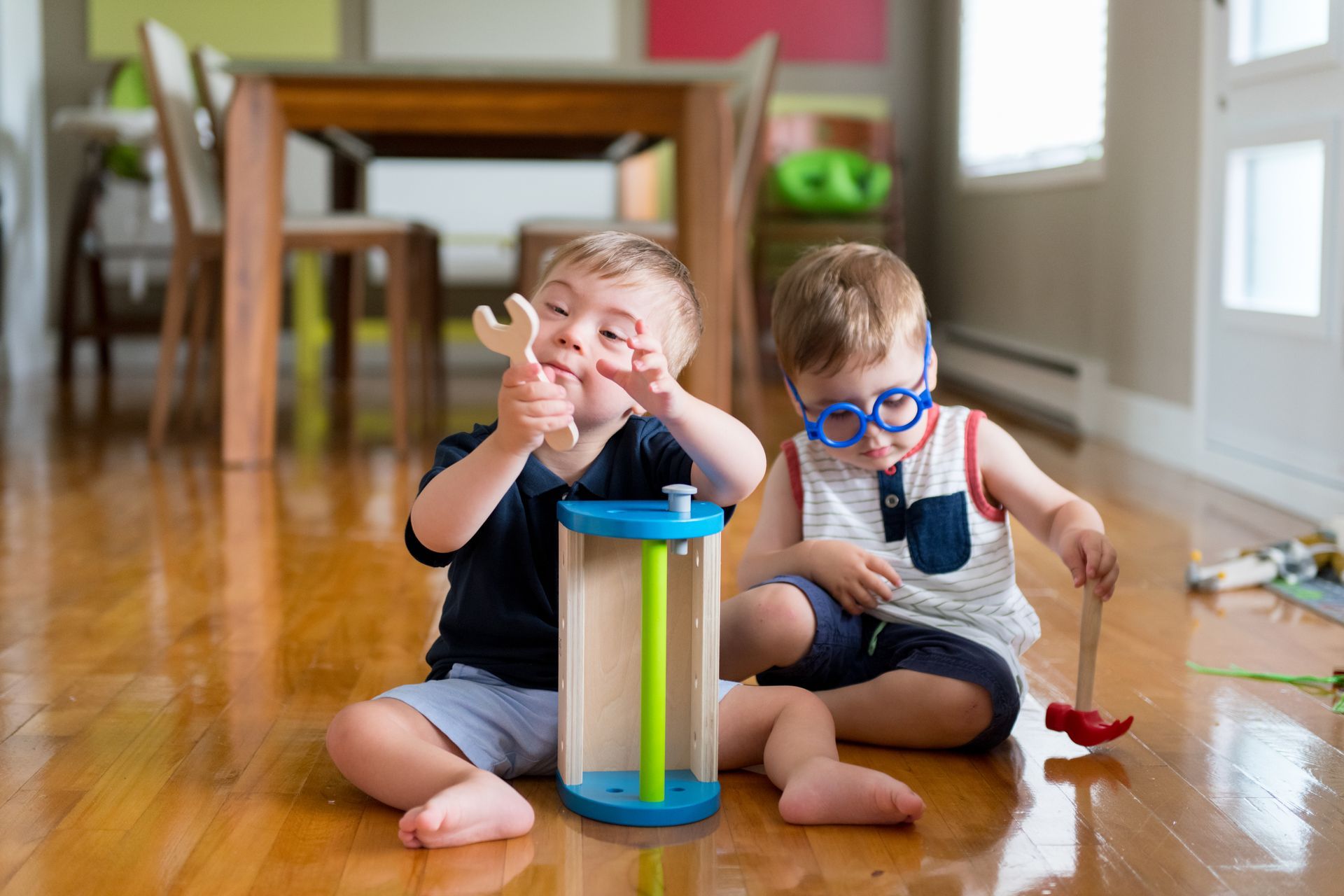 Two young boys are sitting on the floor playing with toys.