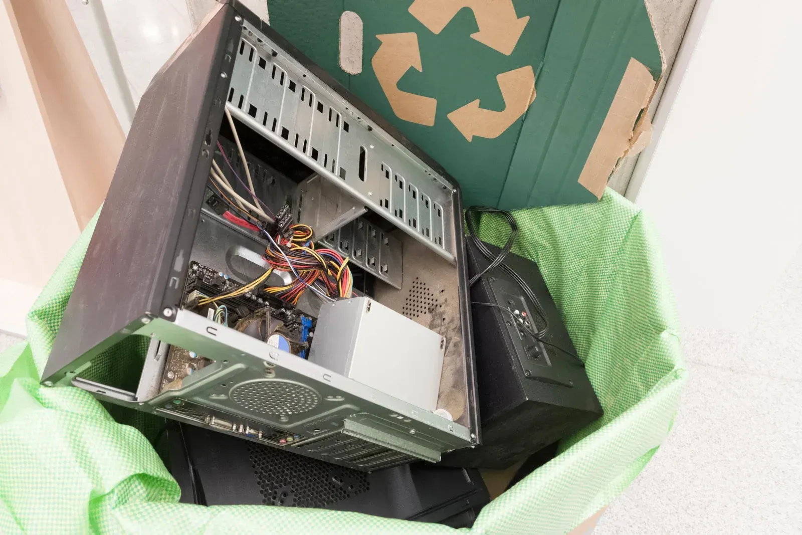 computer components, including a desktop tower and a keyboard, next to a recycle symbol.