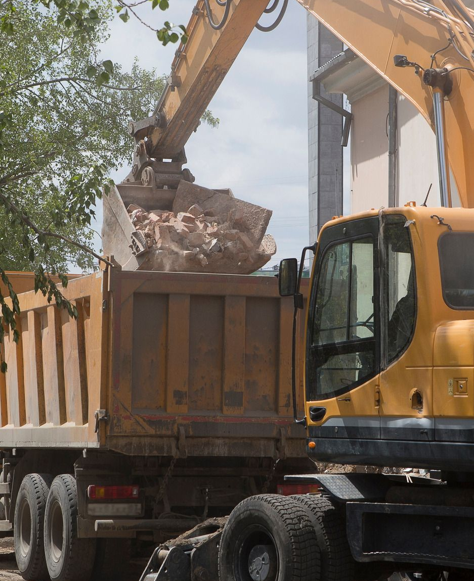 White dumpster overflowing with brick rubble, parked outdoors.