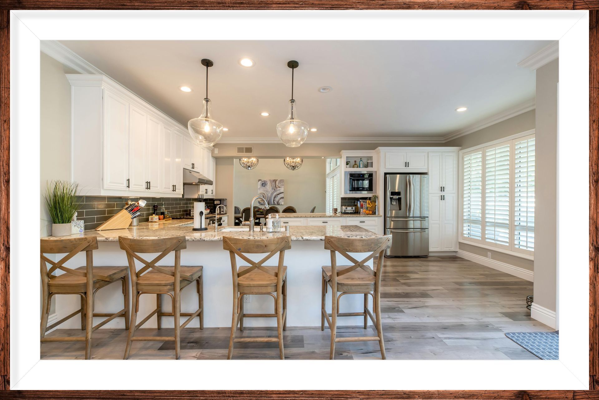 A kitchen with white cabinets , stainless steel appliances , and a large island with stools.