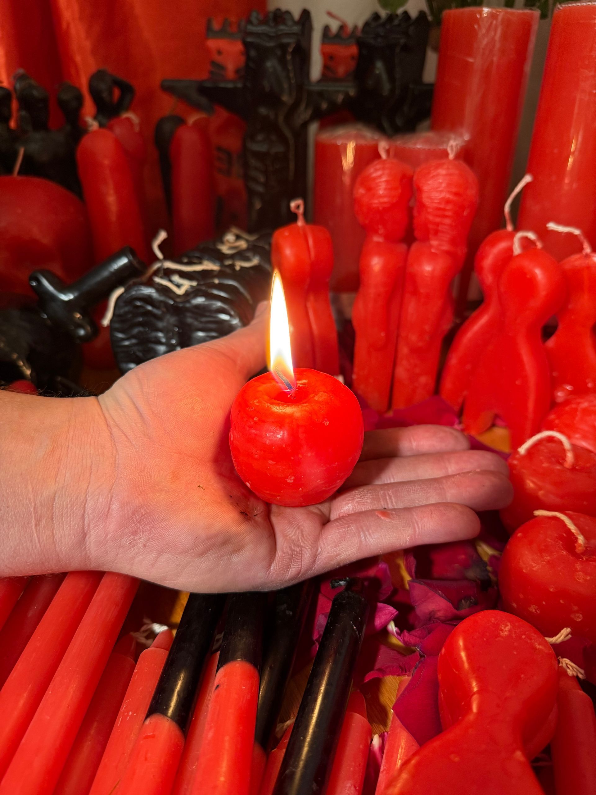 Manos sobre cartas de tarot iluminadas por velas, junto a una bola de cristal.