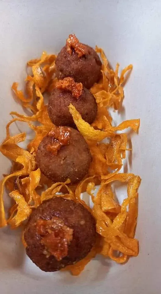 Tre polpette fritte su noodles dorati e croccanti in un vassoio bianco