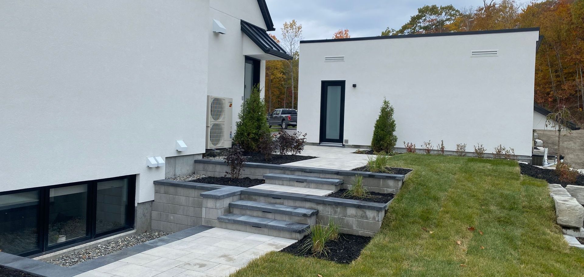 Une maison blanche avec des escaliers qui y mènent et une pelouse devant.