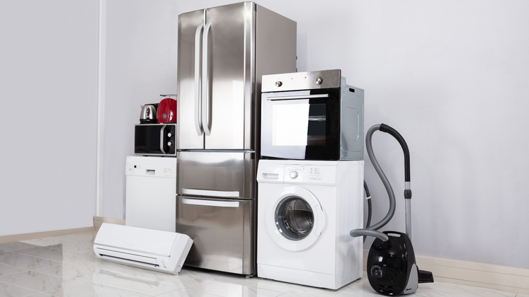 Assortment of white and stainless steel home appliances in a room, including a refrigerator, oven, washing machine, and vacuum cleaner.