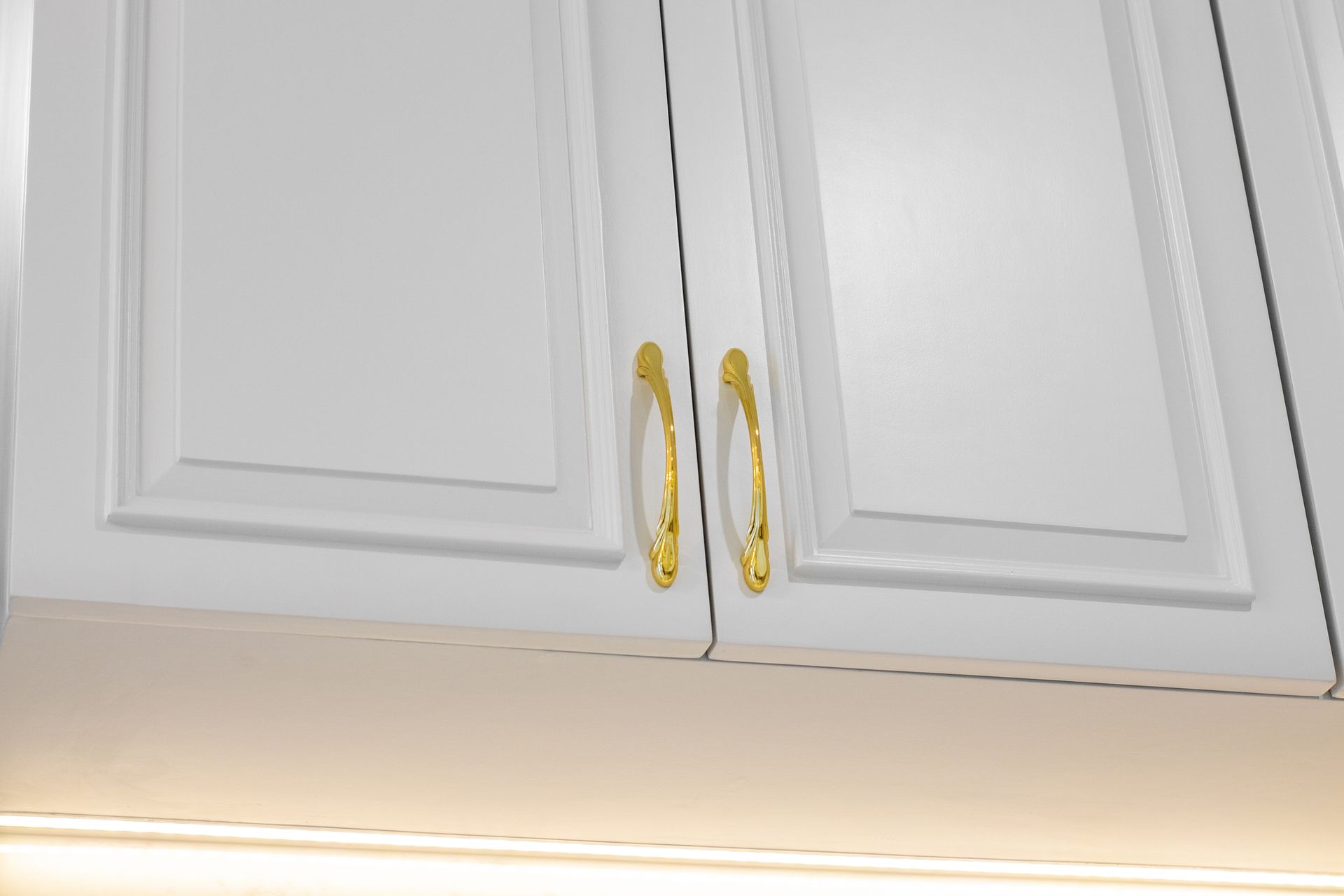A close up of a white cabinet with gold handles.