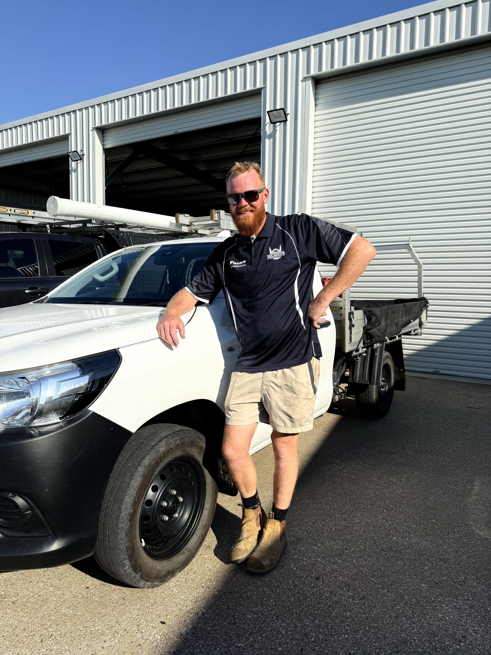 A Man With A Beard Is Standing Next To A White Truck — Beards Refrigeration & Air Conditioning in Bucasia, QLD