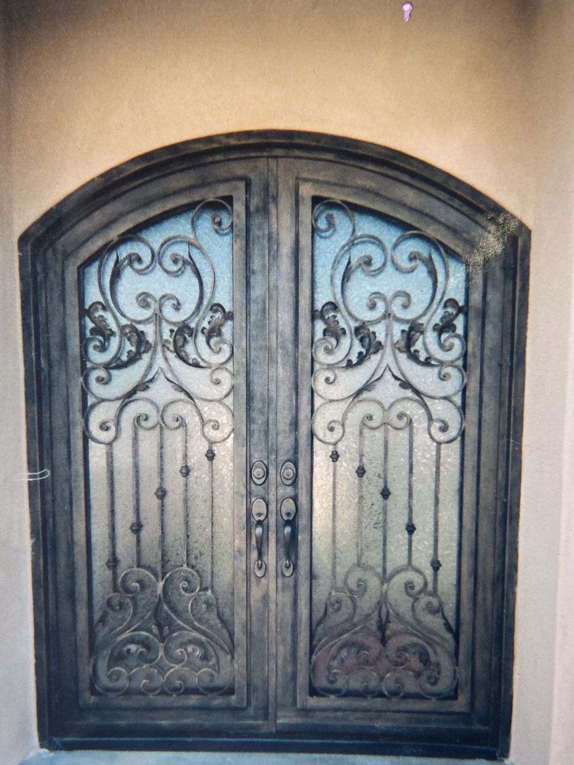 Ornate wrought iron double doors with glass panels and decorative scrollwork.