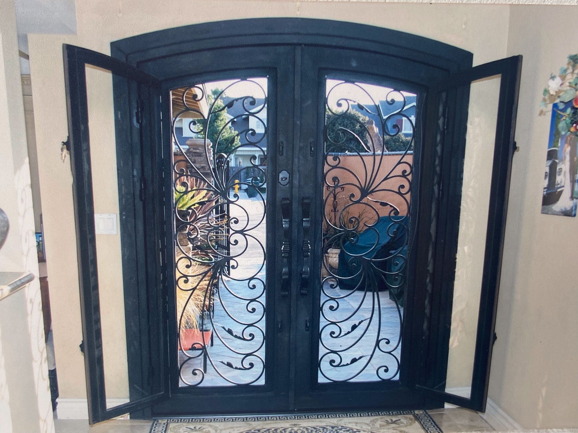 Double black iron entry doors with arched top and decorative scrollwork. Side windows.