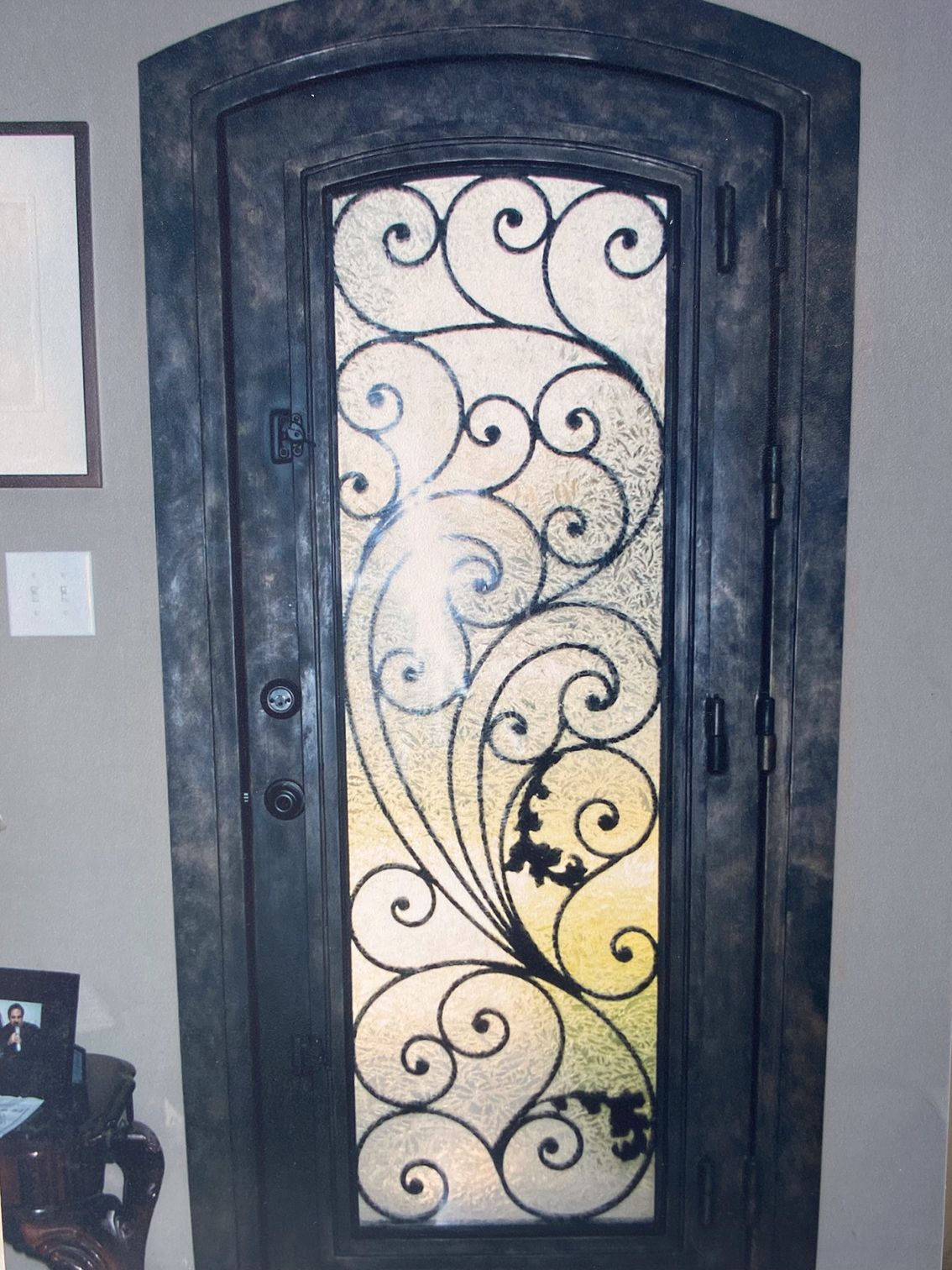 Ornate iron front door with frosted glass and decorative scrollwork.