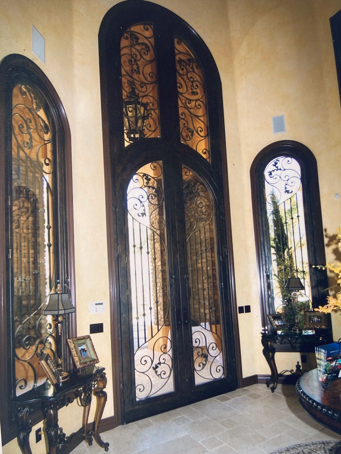 Ornate arched entry doors with decorative ironwork, flanked by tall arched windows.