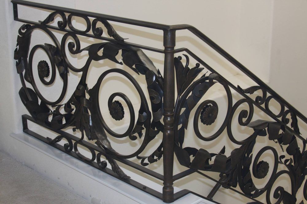 Ornate black wrought iron stair railing with scrolling floral design.