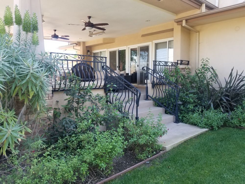 Back patio with wrought iron railings, steps, and lush landscaping.