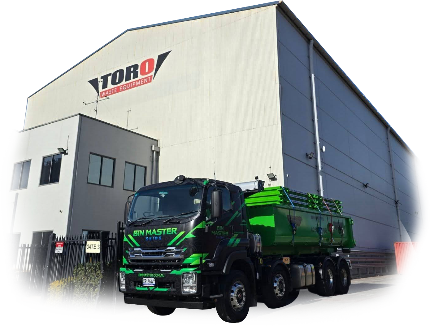 A black and green truck parked in front of a large, beige industrial warehouse with a Toro construction sign.