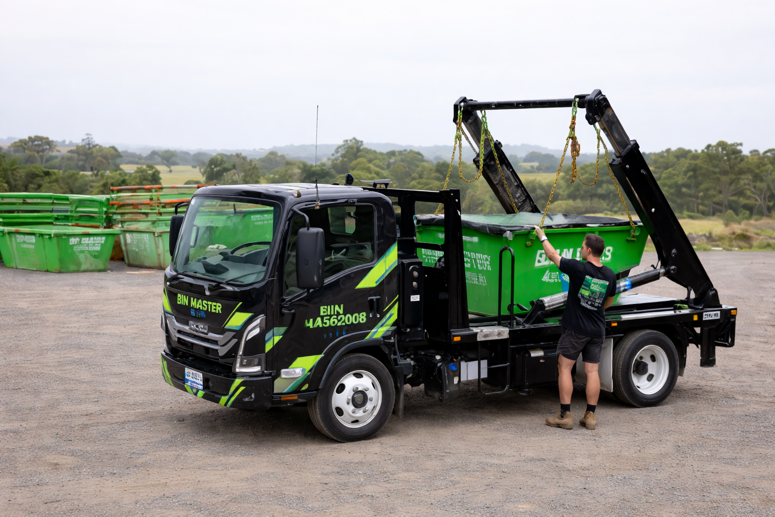 A green dumpster is sitting on top of a dirt field.