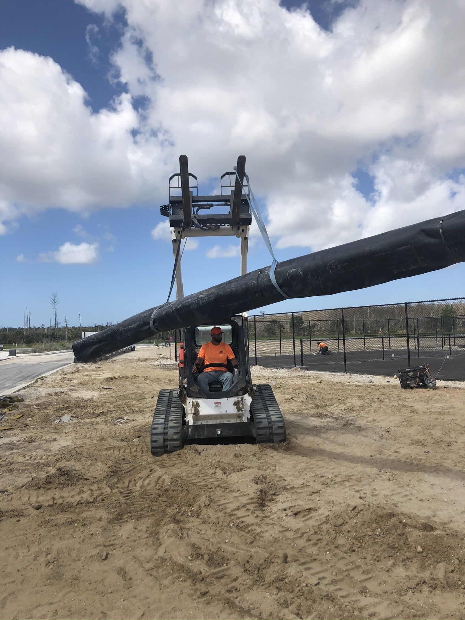 a man is driving a bulldozer carrying a large pipe.