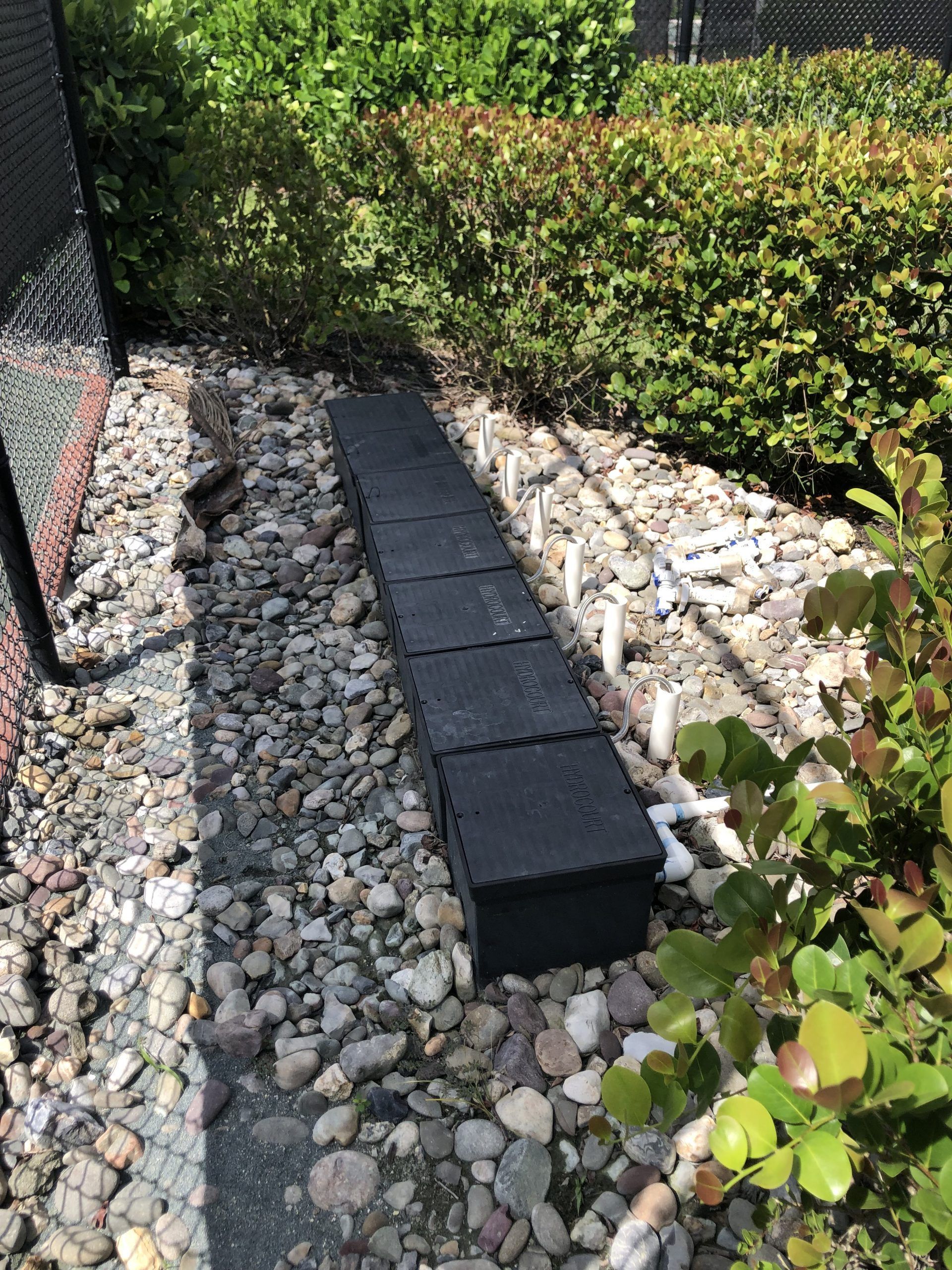 a row of black bricks sitting on top of a pile of rocks in a garden.