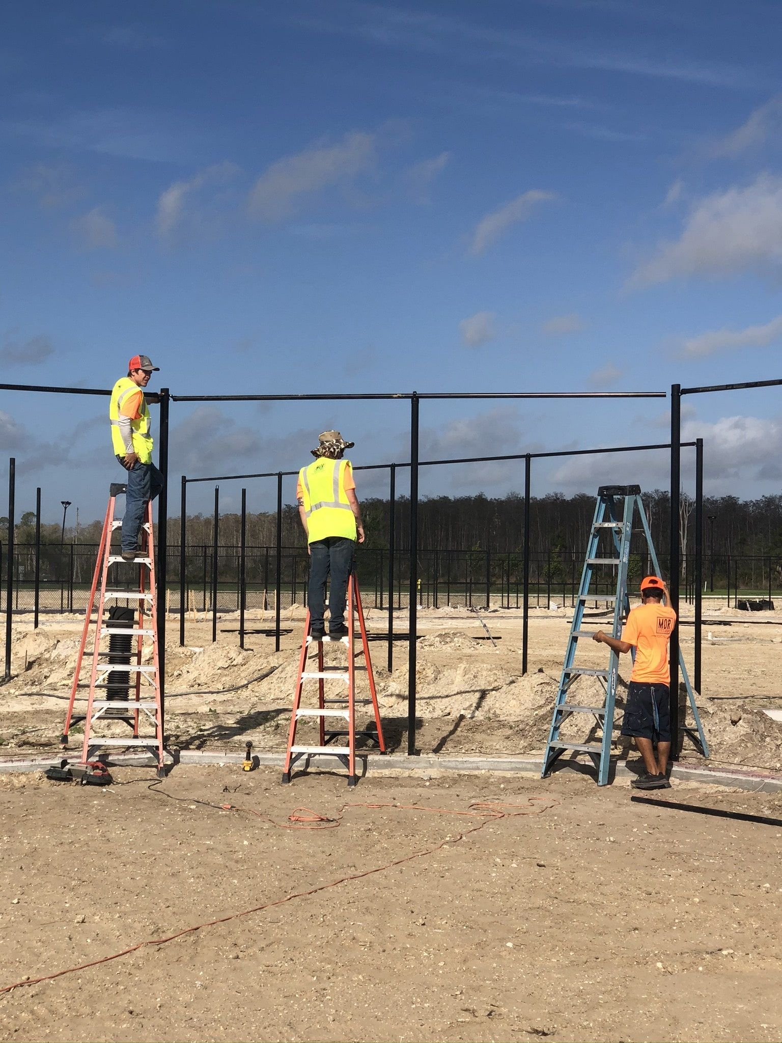 a group of construction workers are working on a fence in a field.