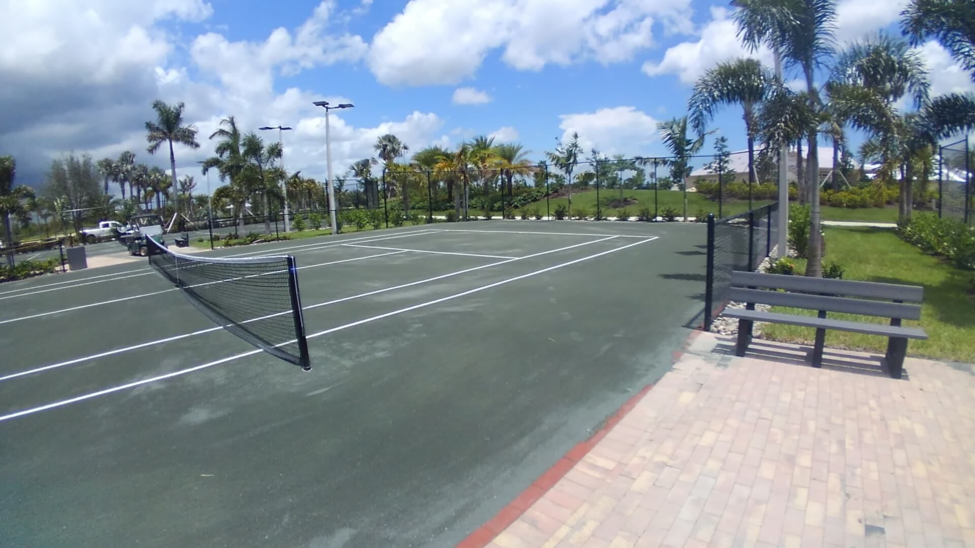 a tennis court with a bench in the foreground