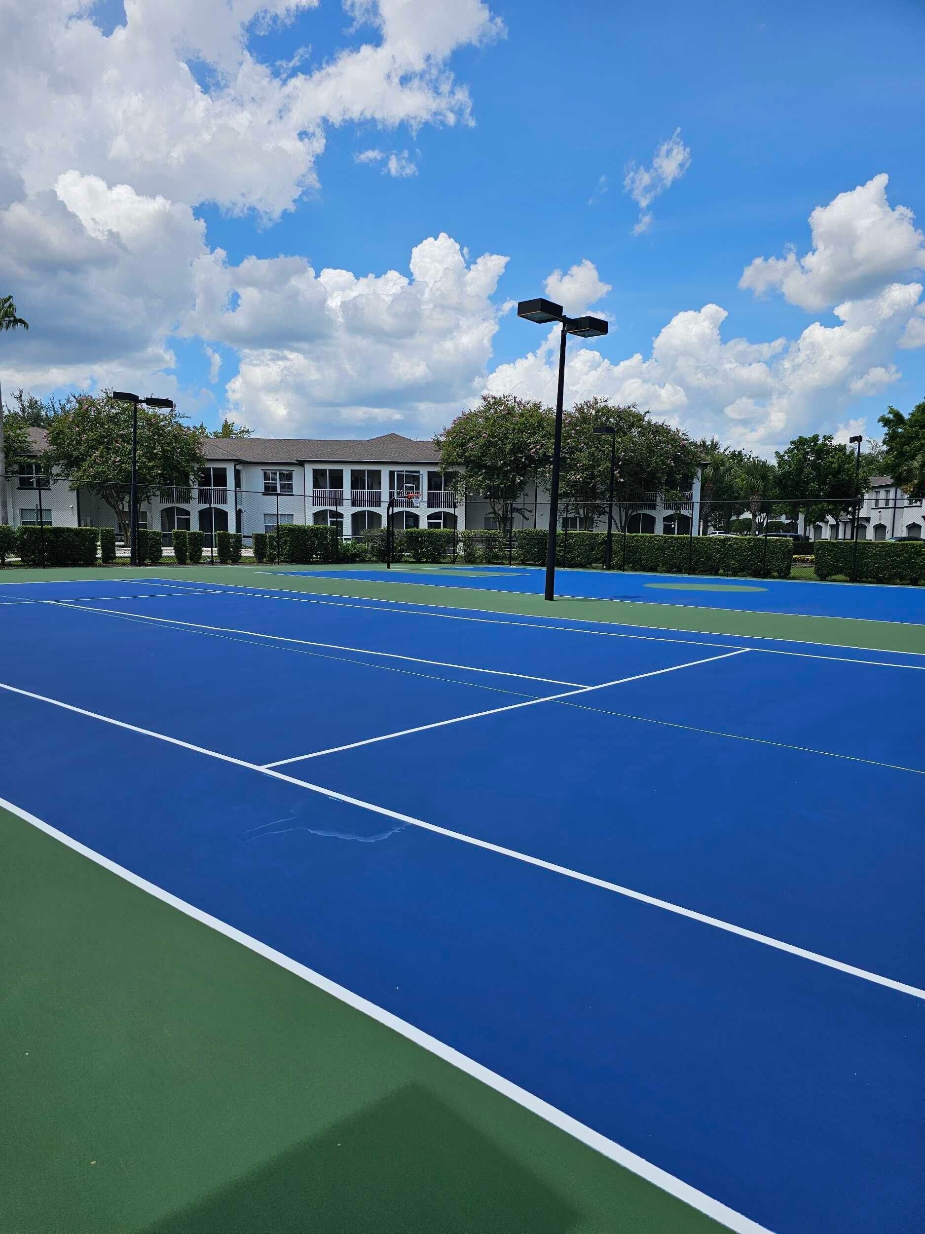 A blue tennis court with a building in the background
