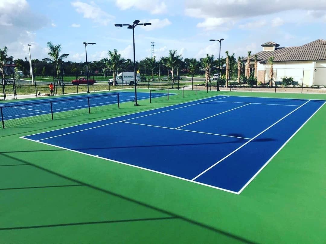 a blue and green tennis court with a building in the background