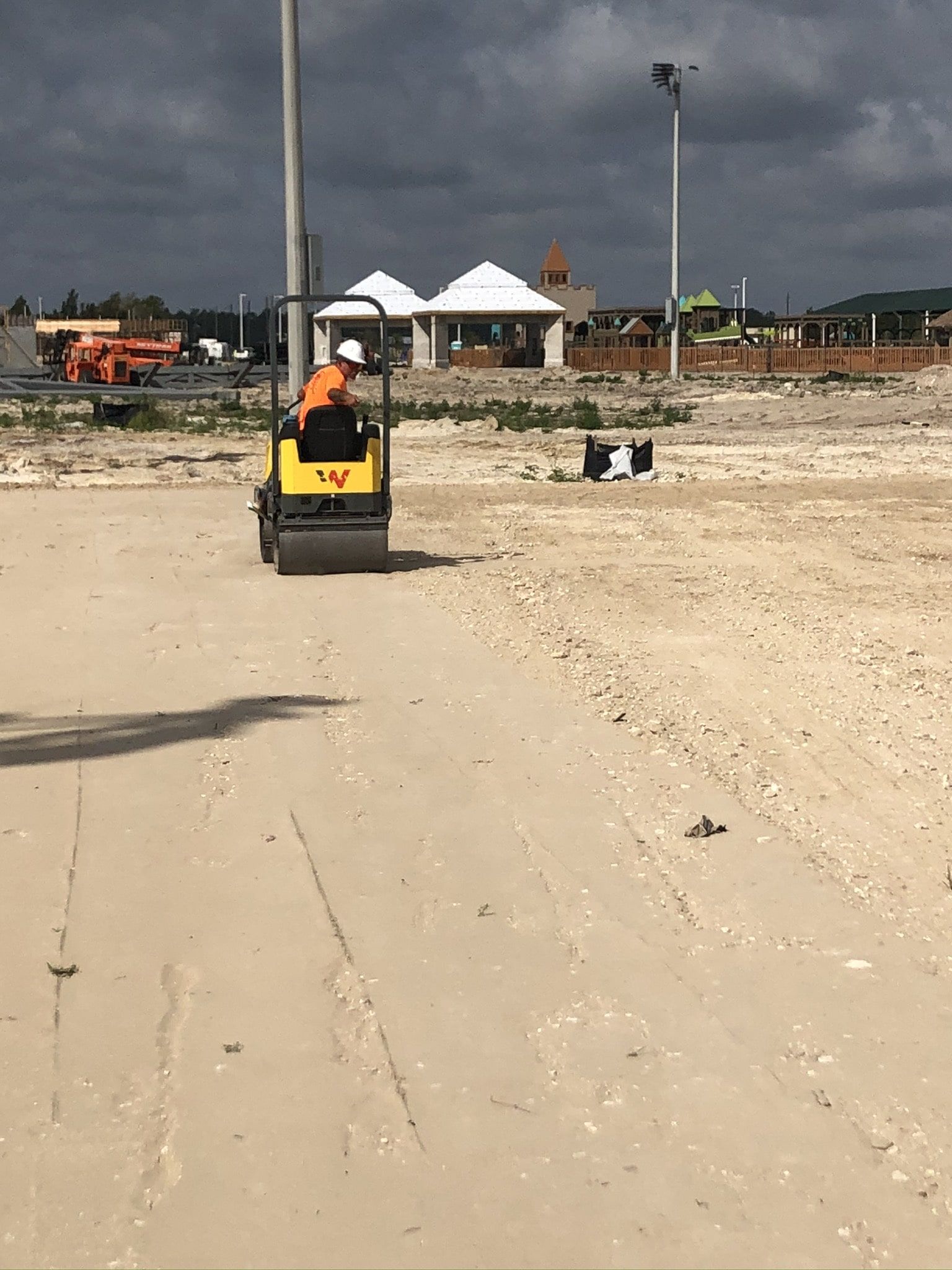 a man is driving a yellow roller on a dirt road.