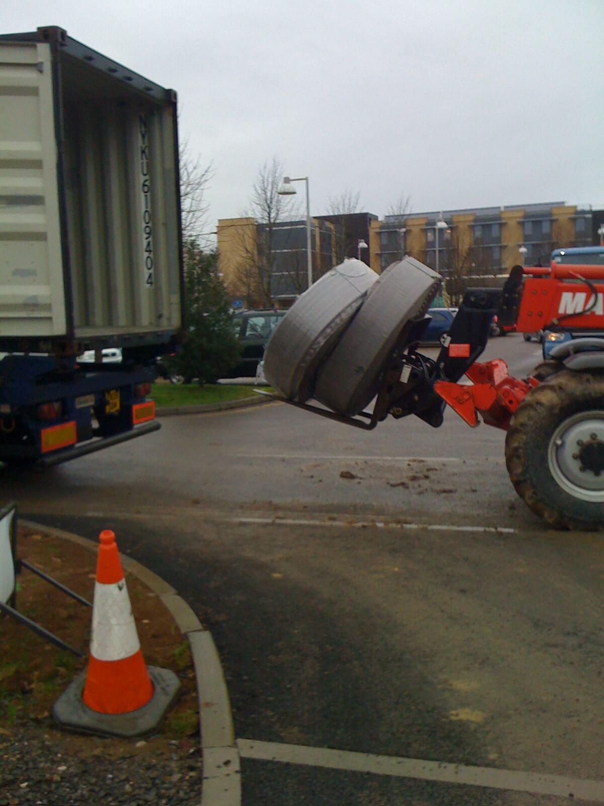 a man lifts a container with a machine that says manitou on it