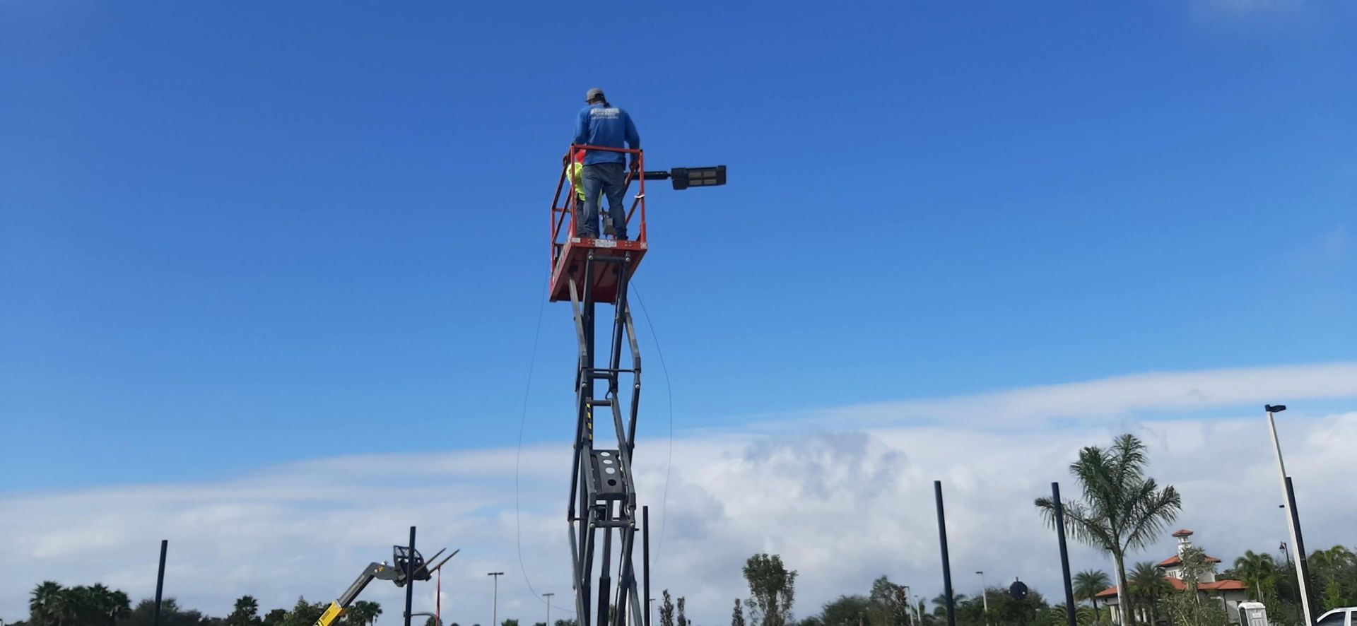 a man is standing on a lift working on a street light.