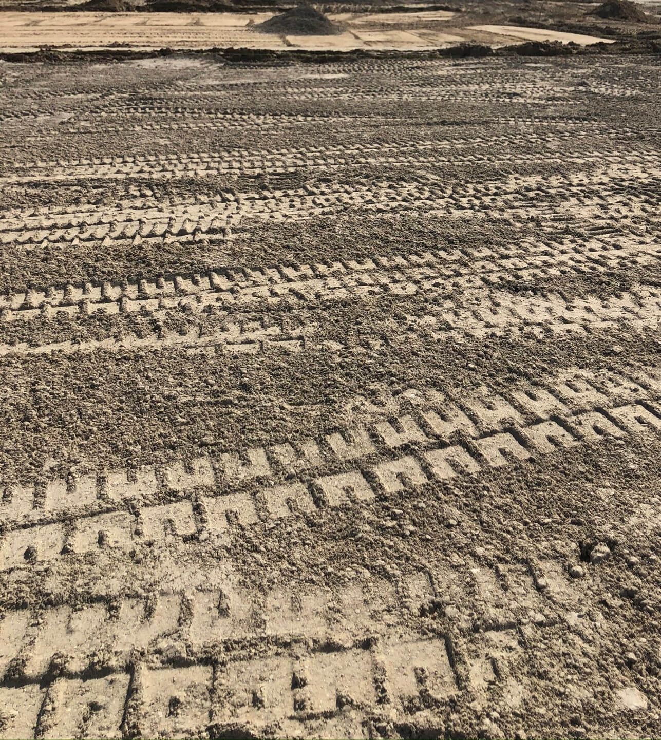 a black and white photo of tire tracks in a field.
