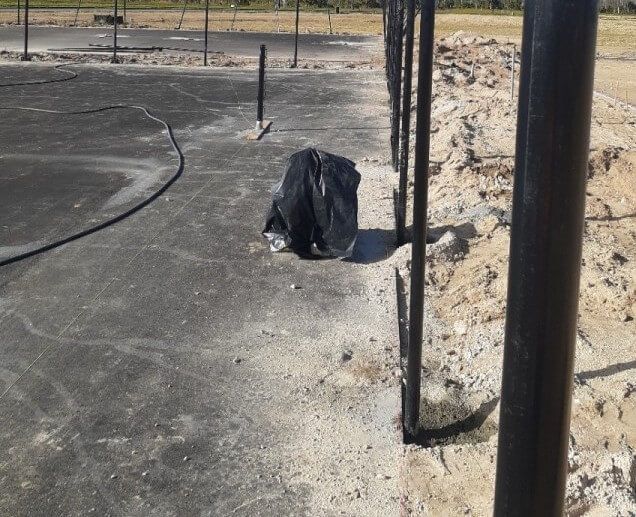 a black bag is laying on the ground near a fence