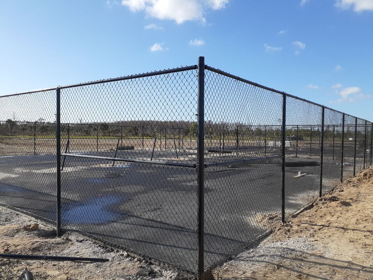 a chain link fence is surrounding a basketball court.
