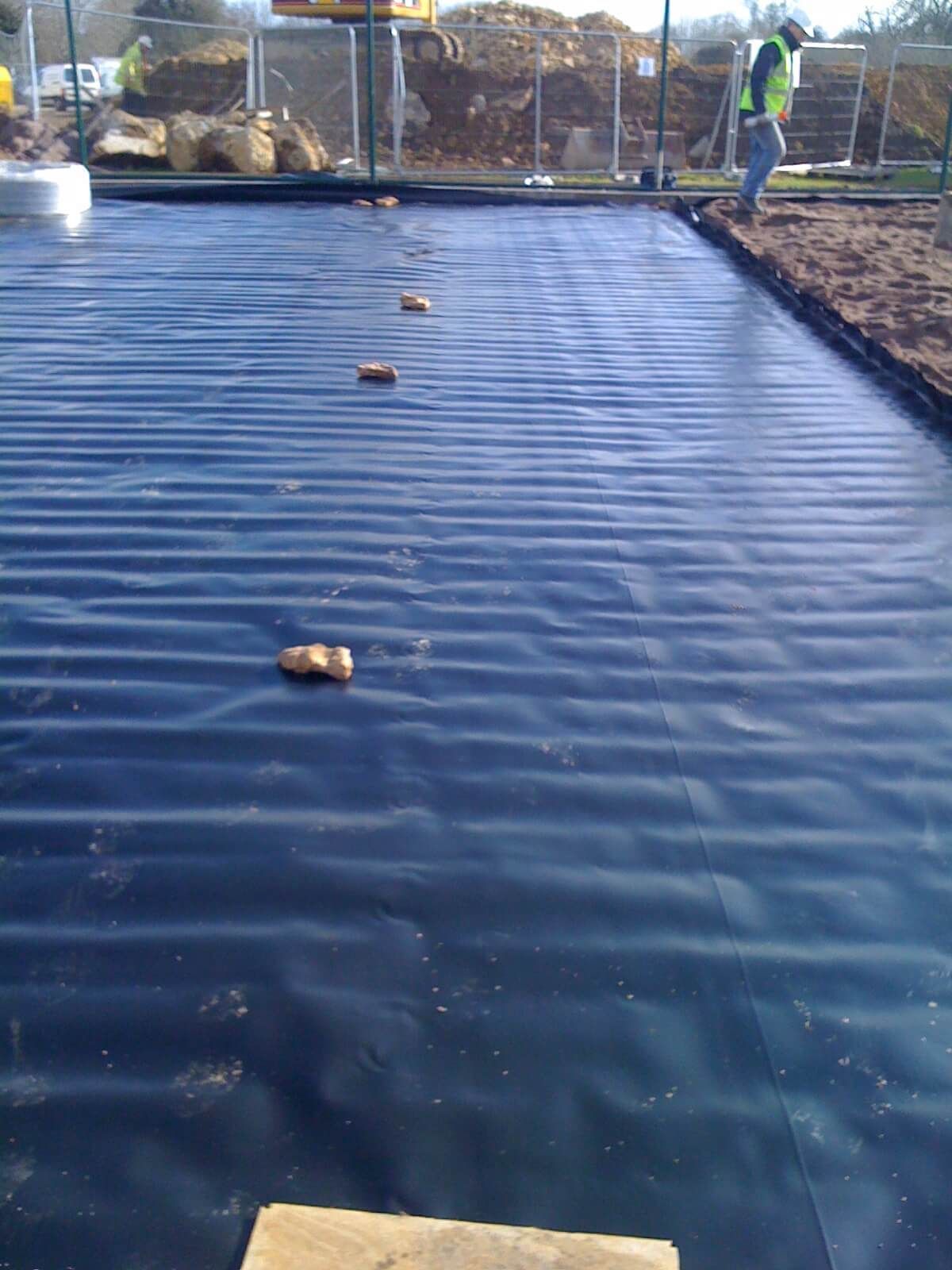 a man in a green vest is walking on a black tarp