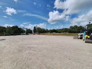 A row of construction vehicles are parked in a parking lot.