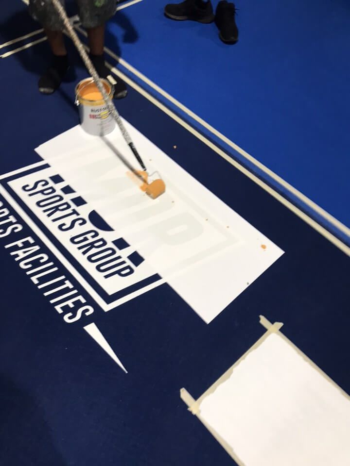 a person is painting a sign that says sports group on it