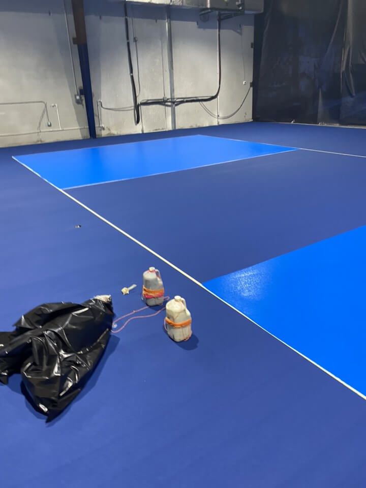 a blue tennis court with two bottles on the floor