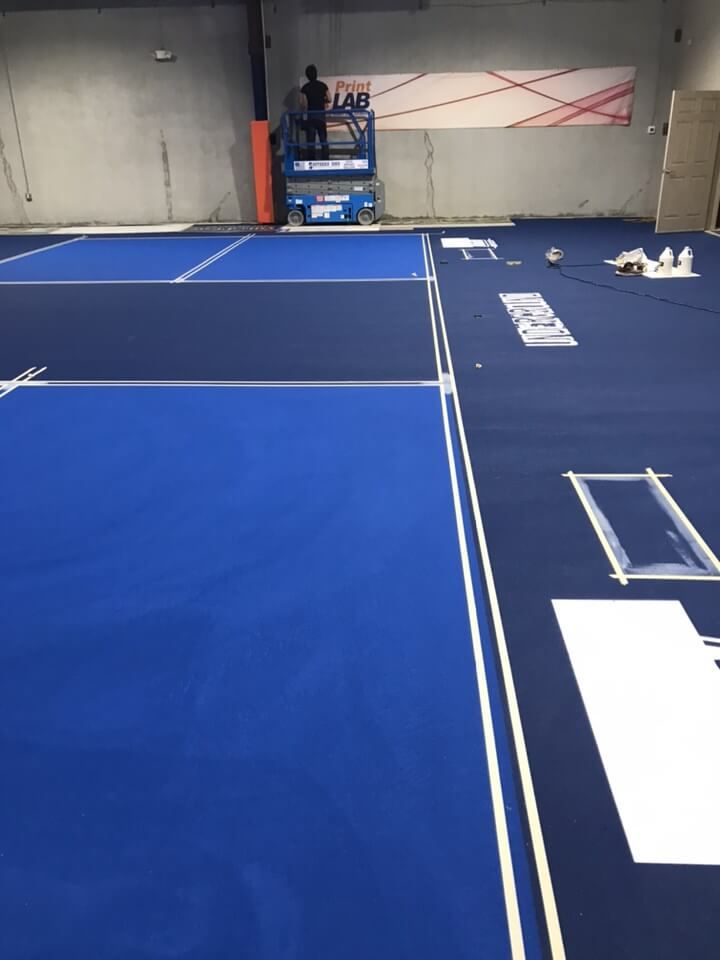 a tennis court is being painted blue and white