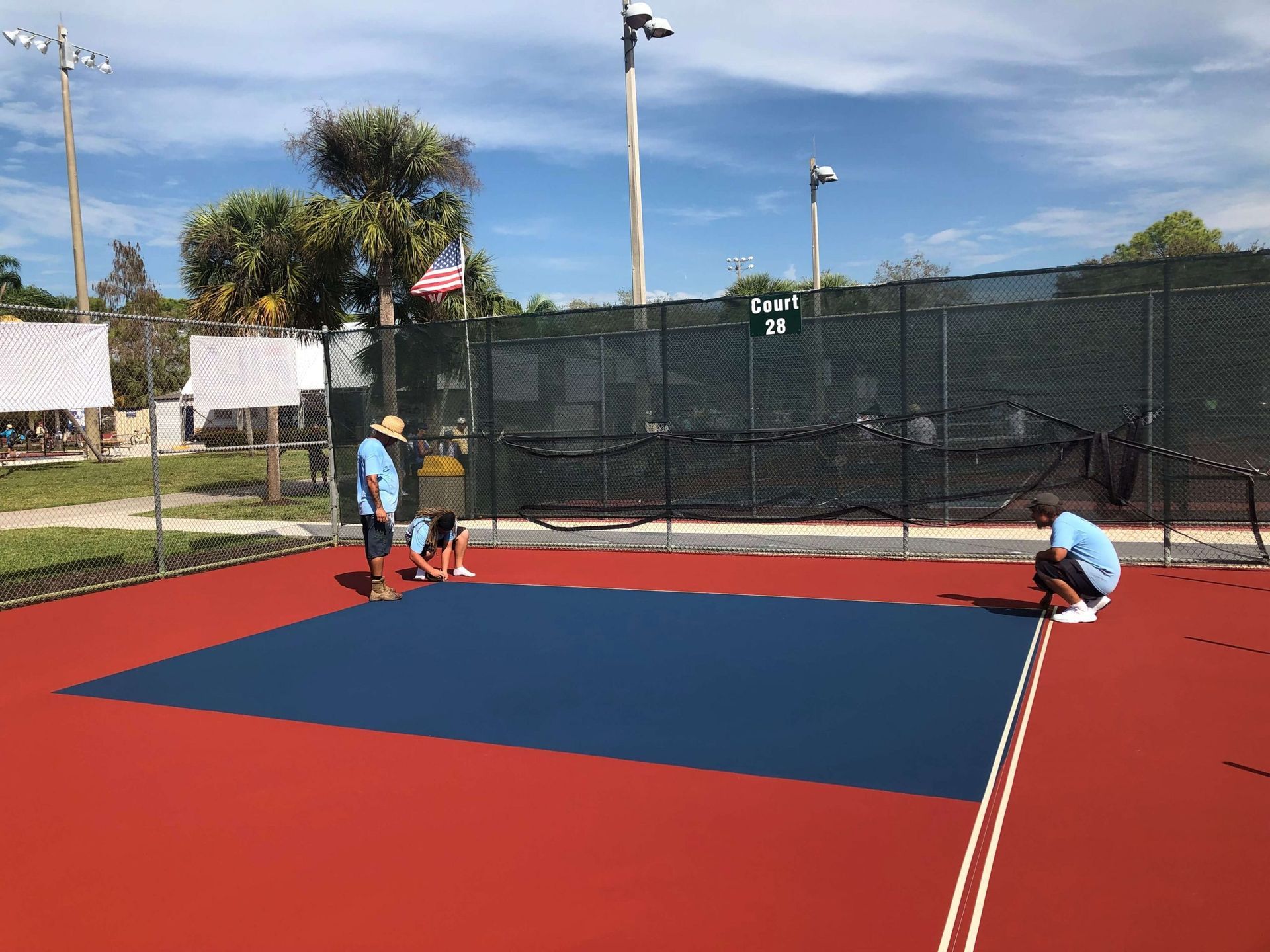 a group of people are working on a tennis court.
