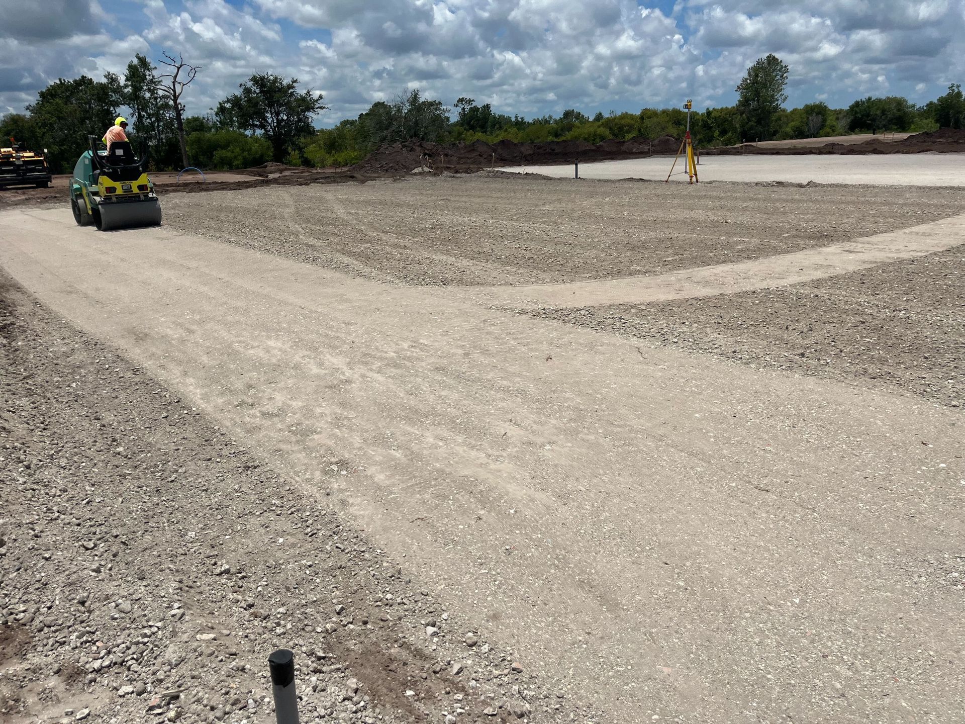 a roller is rolling gravel on a dirt road.