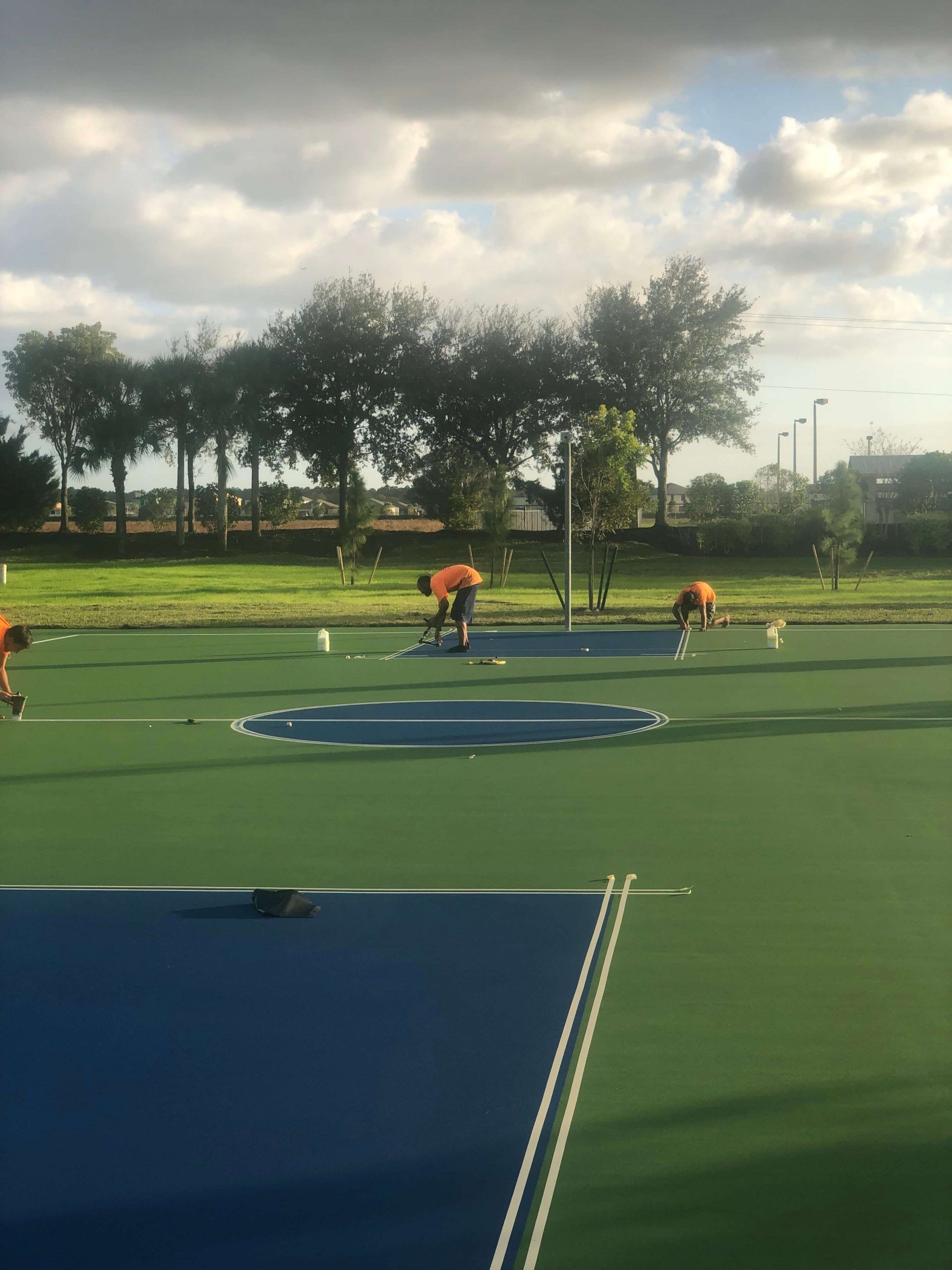 a group of people are working on a tennis court