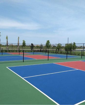 A tennis court with blue and red courts and a fence