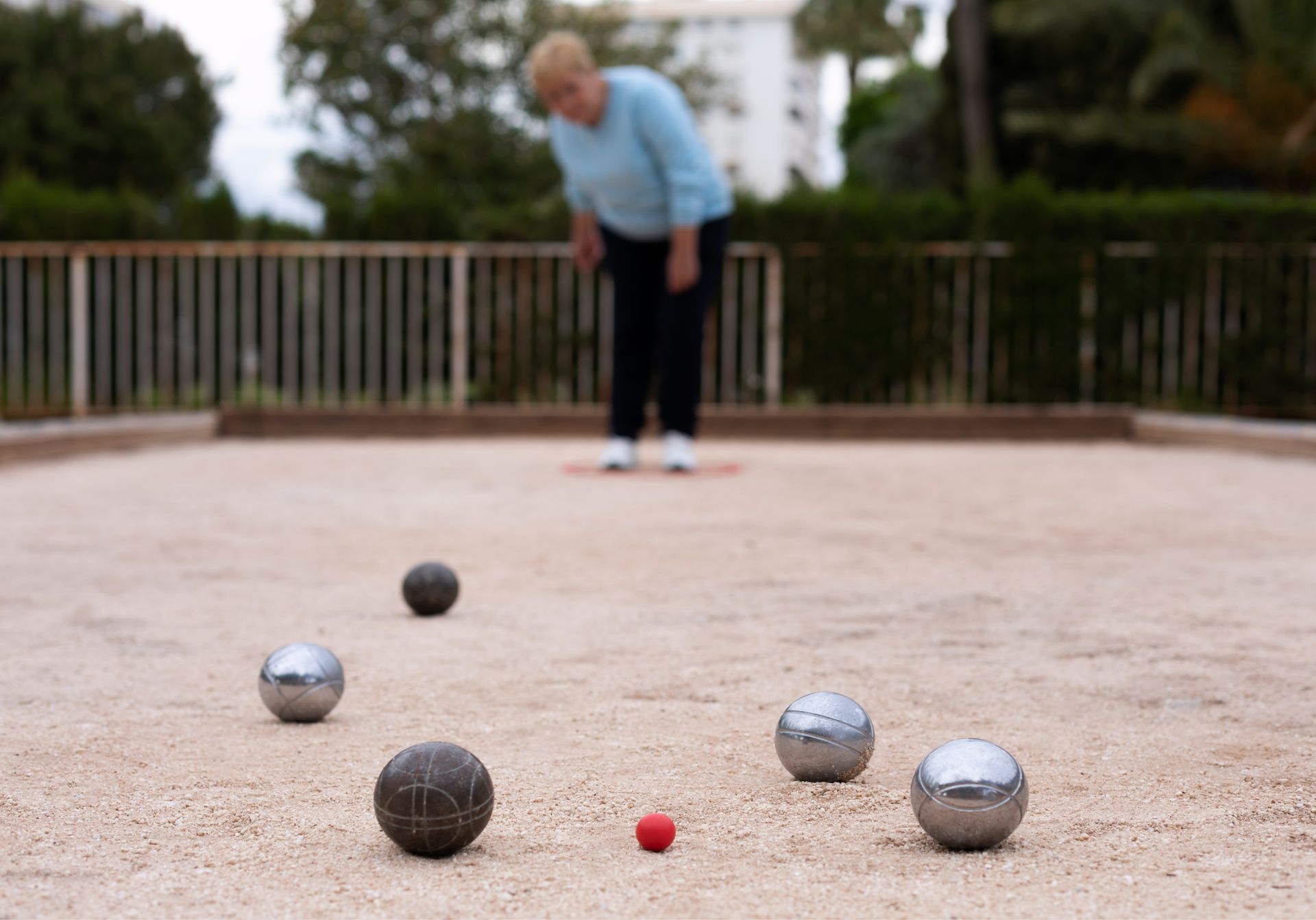 A woman is playing a game of bocce ball in a park.