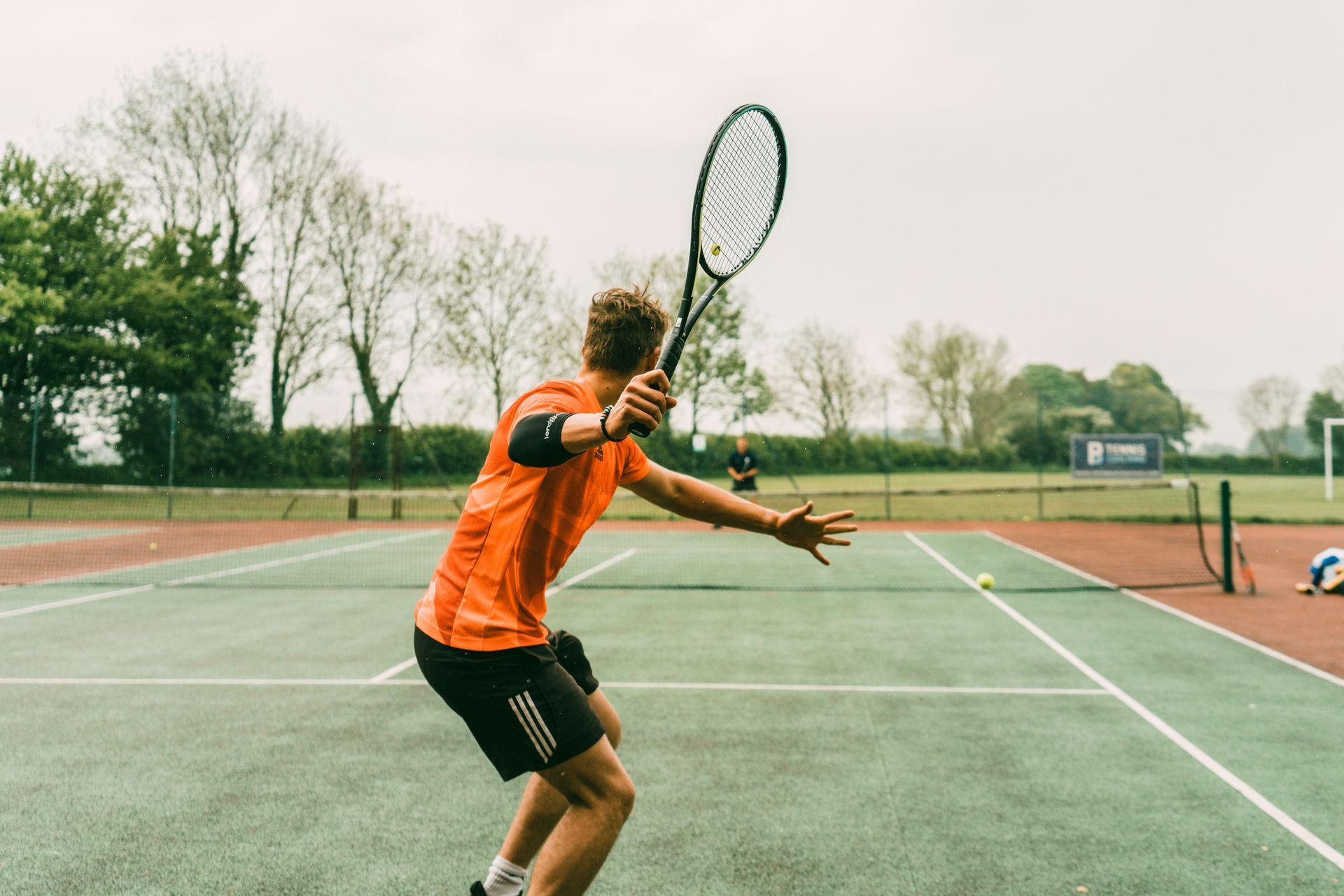 A man is holding a tennis racquet on a tennis court.