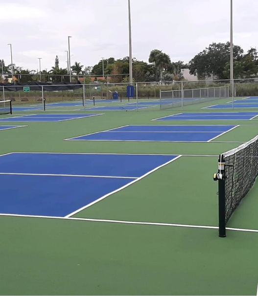 A tennis court with blue and red courts and a fence