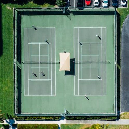 an aerial view of a tennis court with people playing tennis.
