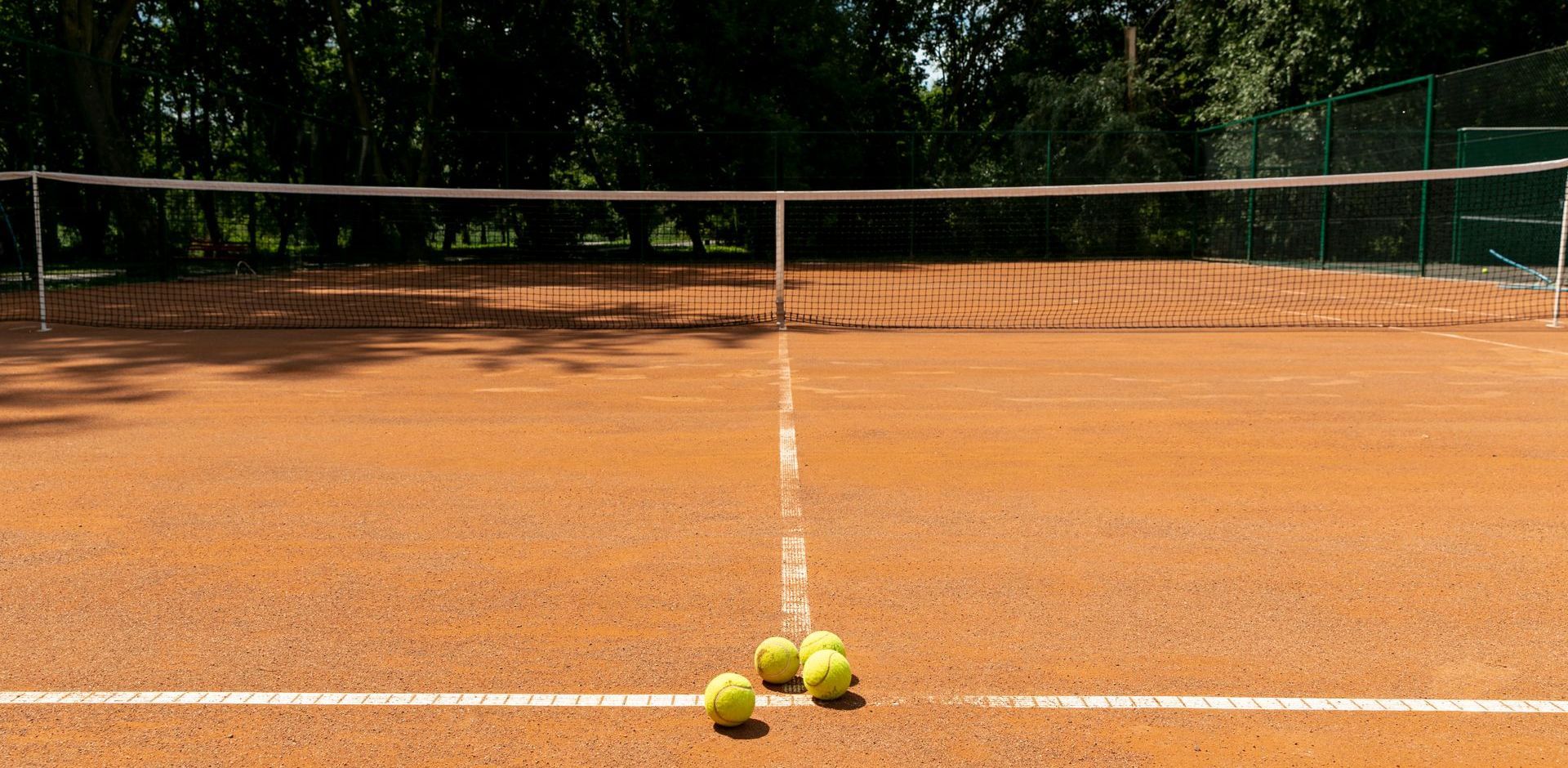 Three tennis balls are on the court near the net.