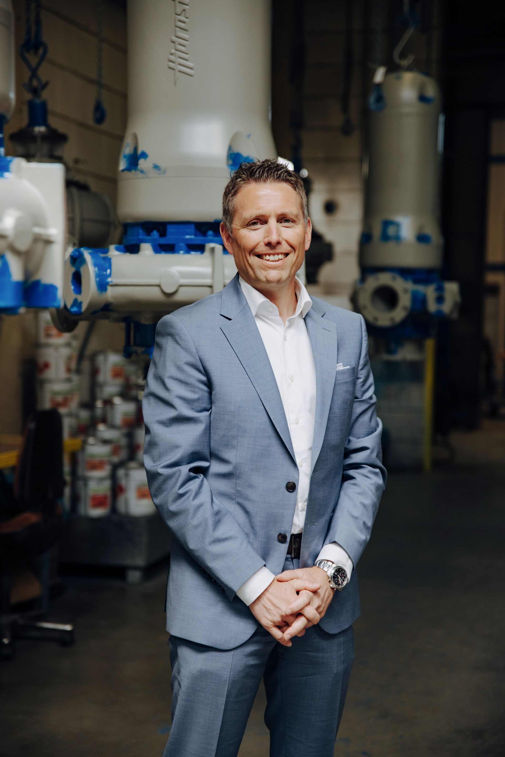 Rolf Schweizer, CEO of  Hidrostal, in einem Anzug und einem weissen Shirt steht vor einer Maschine.