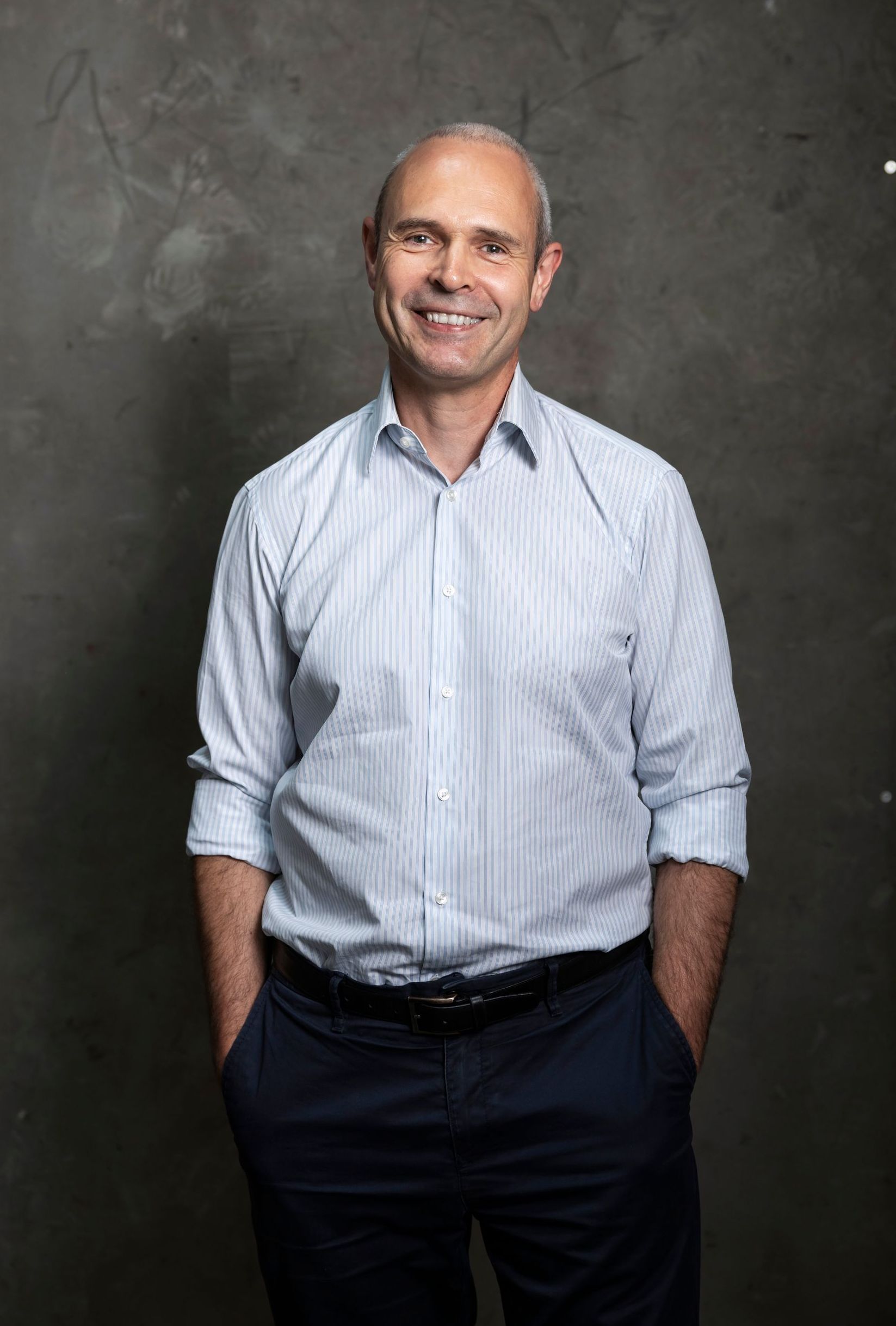 PD Dr. med Christoph Müller-Pfeiffer, CEO Salomo AG, wearing striped shirt and blue pants, standing with hands in pockets.