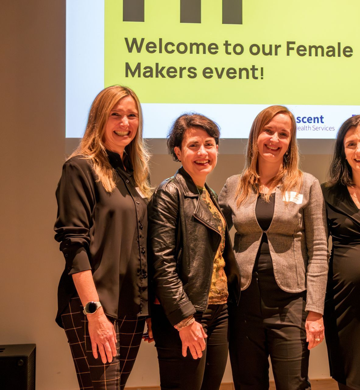 Eine Gruppe von Frauen steht nebeneinander vor einem Schild mit der Aufschrift „Hallo“.