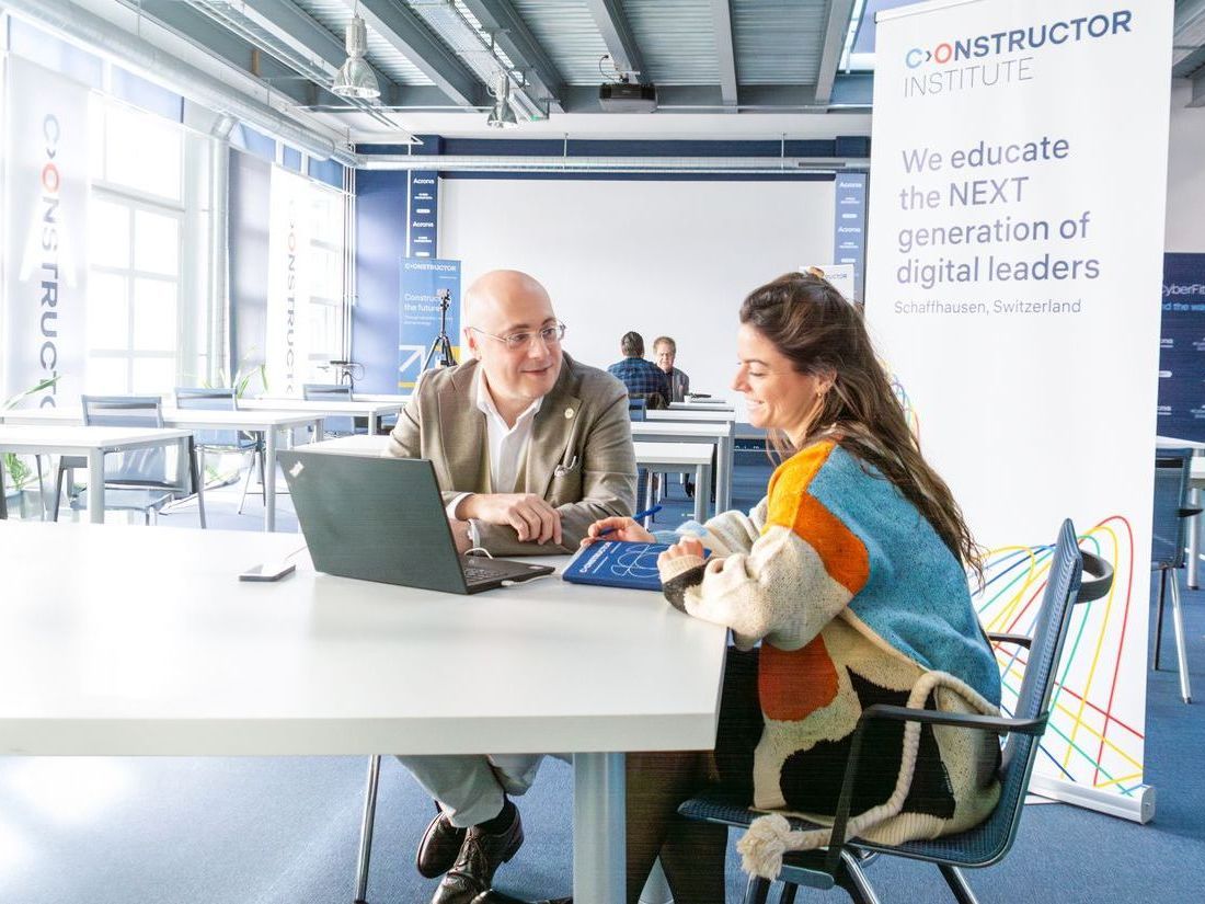 Ein Mann und eine Frau sitzen mit einem Laptop an einem Tisch.