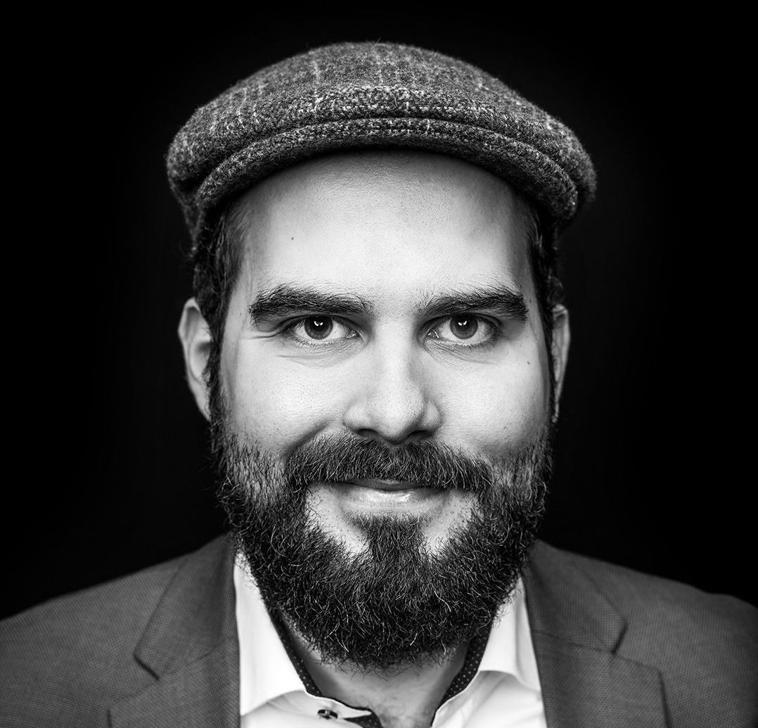 Ein Schwarzweissfoto eines Mannes mit Bart und Hut.